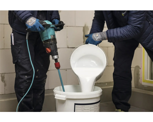 Handwerker mischen Farbe mit einem Farbmischer in einem Eimer.