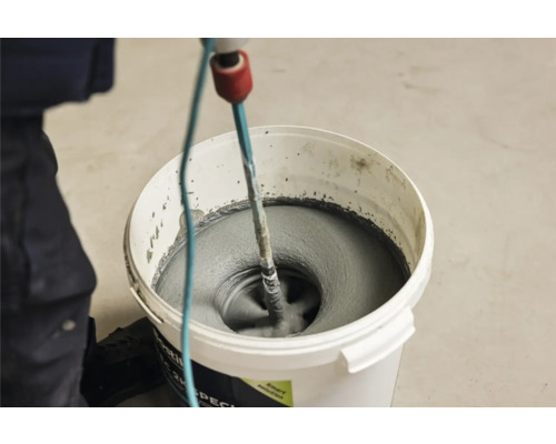 Mörtel wird in einem Eimer mit einem Rührwerk gemischt.