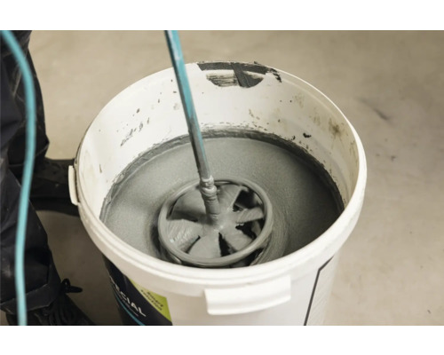 Mörtel wird mit einem Rührwerk in einem Eimer gemischt.