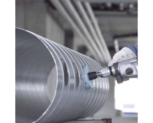 Eine Person verwendet eine Bohrmaschine mit Bürstenaufsatz zur Bearbeitung eines Metallrohrs.