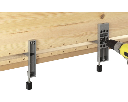 Holzbrett wird mit einer Bohrmaschine und einer Bohrlehre bearbeitet