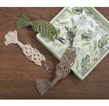 Drei Makramee-Schlüsselanhänger mit Quasten auf Holzgrund