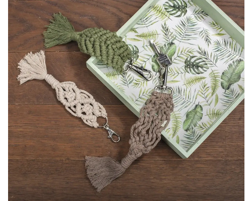 Drei Makramee-Schlüsselanhänger mit Quasten auf Holzgrund