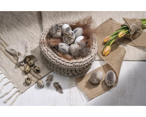 Dekorative Ostereier in einem Korb mit Federn, Tulpen und Wachteleiern