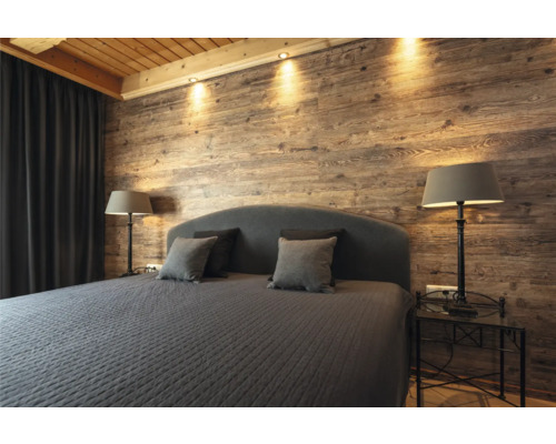 Schlafzimmer mit Holzwand, Bett, Nachttischen und Lampen