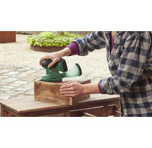 Eine Person schleift mit einem Akku-Exzenterschleifer von Bosch ein Holzstück.