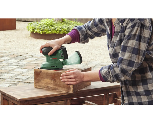 Eine Person schleift mit einem Akku-Exzenterschleifer von Bosch ein Holzstück.