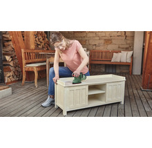 Frau schleift Holzkommode mit einem Exzenterschleifer im Außenbereich.