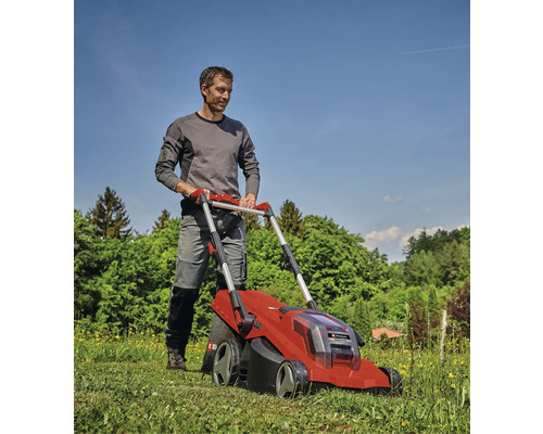 Mann beim Rasenmähen mit einem roten Akku-Rasenmäher im Garten.