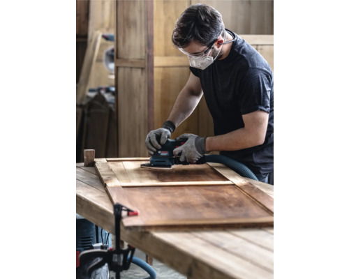 Mann schleift Holz mit einem Schwingschleifer