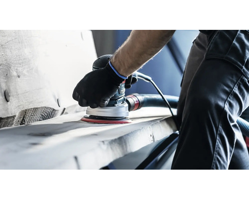 Eine Person schleift mit einem Exzenterschleifer ein Werkstück.