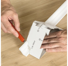 Eine Person schneidet mit einem Universalmesser ein Verpackungsteil.