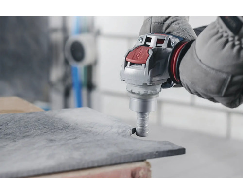 Handwerker bearbeitet Steinplatte mit einem Bohrgerät