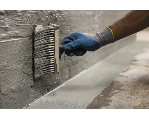 Auftragen von Dichtungsschlämme mit einer Bürste auf eine Wand