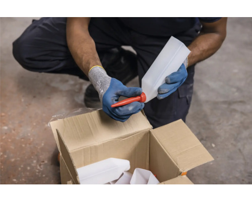 Eine Person befestigt einen Ausgießer an einer Plastikflasche über einem Karton