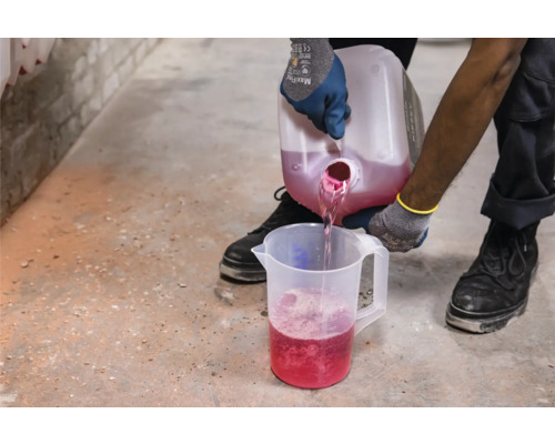 Flüssigkeit wird von einem Behälter in einen Messbecher gegossen