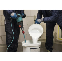 Handwerker mischen Farbe mit einem Farbmischer in einem Eimer.