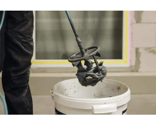 Mörtel wird mit einem Rührwerk in einem Eimer gemischt.