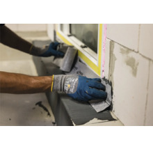 Handwerker bringt Dichtungsband an Fenster an