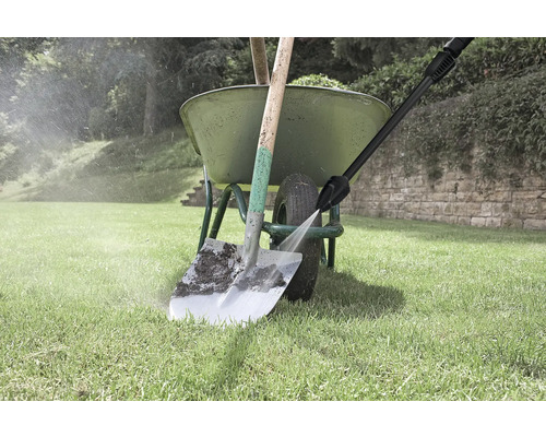 Szene im Garten: Eine Schubkarre mit einer Schaufel wird mit einem Hochdruckreiniger gereinigt.