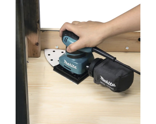 Makita Schwingschleifer mit Staubbeutel wird von einer Hand gehalten.