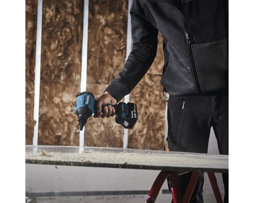 Eine Person benutzt einen Akku-Trockenbauschrauber der Marke Makita, um eine Trockenbauwand zu verschrauben.