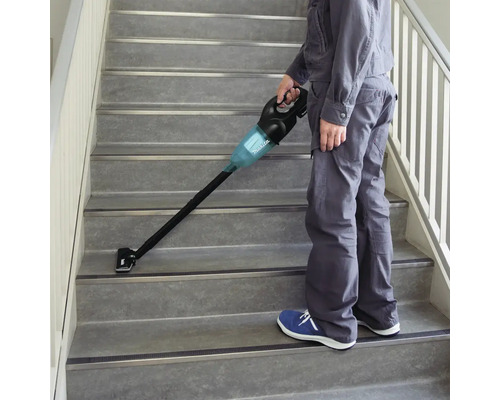 Eine Person saugt eine Treppe mit einem Akku-Staubsauger der Marke Makita.