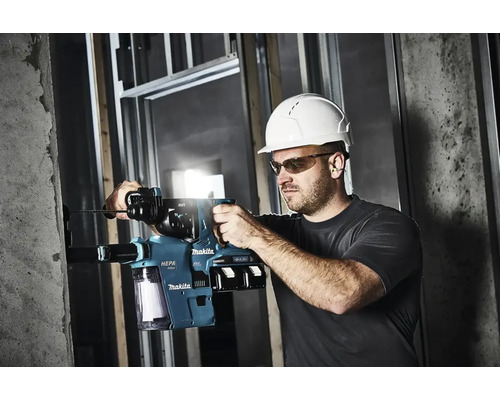 Mann mit Schutzhelm und Schutzbrille bohrt mit einem Makita Bohrhammer ein Loch in eine Betonwand.