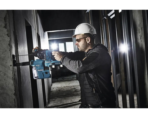 Ein Bauarbeiter mit Schutzhelm und Schutzbrille bohrt mit einem Makita Bohrhammer in eine Wand.