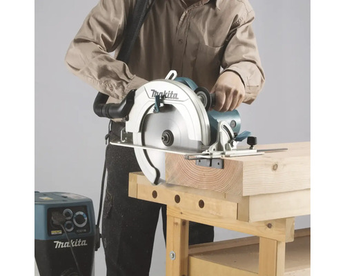Eine Person sägt mit einer Makita Handkreissäge ein Holzbrett auf einer Werkbank.