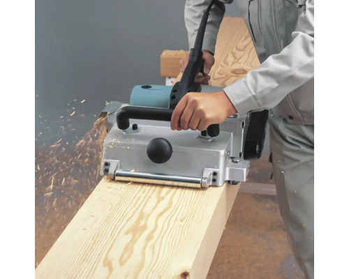 Ein Hobel bearbeitet ein Holzbrett und erzeugt Späne.