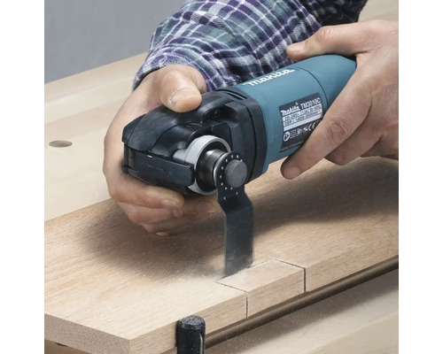 Makita Multifunktionswerkzeug beim Schneiden eines Holzstücks