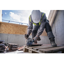 Ein Bauarbeiter schneidet mit einer Trennscheibe Dachziegel auf einer Palette