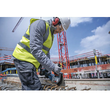 Ein Bauarbeiter benutzt einen Winkelschleifer auf einer Baustelle.