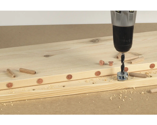 Holzbretter werden mit einer Bohrmaschine, Dübeln und Hülsen verbunden.