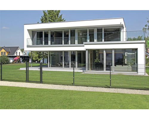Modernes Haus mit großflächigen Fenstern und einem Zaun im Garten.