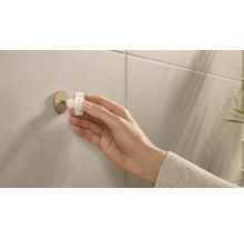 Eine Hand montiert einen Handtuchhaken an einer gefliesten Wand