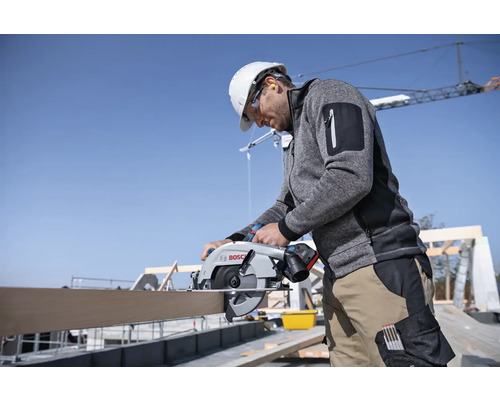 Handwerker sägt mit einer Akku-Kreissäge ein Holzbrett. Bosch Logo.