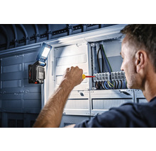 Ein Elektriker arbeitet an einem Verteilerkasten mit einer Bosch Arbeitsleuchte.