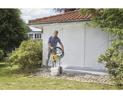 Mann bereitet eine Farbspritzanlage im Garten vor einem Gebäude vor.