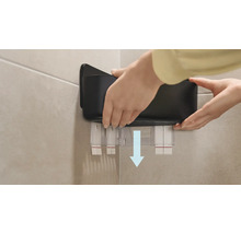 Person befestigt einen schwarzen Wandorganizer an der Wand