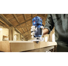 Eine Person verwendet eine Oberfräse von Bosch Professional an einem Werkstück aus Holz.