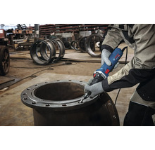 Ein Mann benutzt einen Geradschleifer an einem Metallrohr.