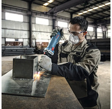 Ein Arbeiter verwendet eine Schleifmaschine zum Bearbeiten von Metall in einer Werkstatt.