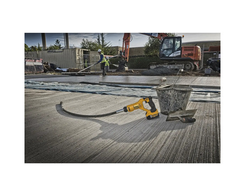 Betonrüttler im Einsatz auf einer Baustelle mit weiteren Bauwerkzeugen und einem Bagger im Hintergrund