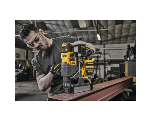 Ein Mann bohrt mit einer gelben Magnetbohrmaschine in ein Metallstück.