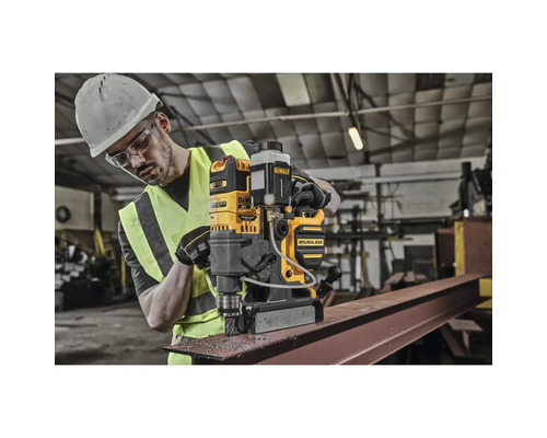Mann bedient eine gelbe DeWalt Magnetbohrmaschine an einem Metallträger.