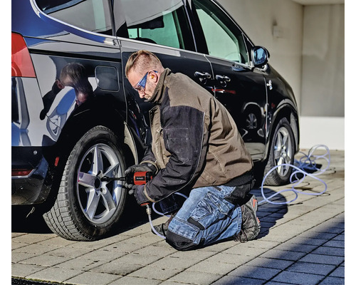 Mann benutzt einen Schlagschrauber am Reifen eines Autos