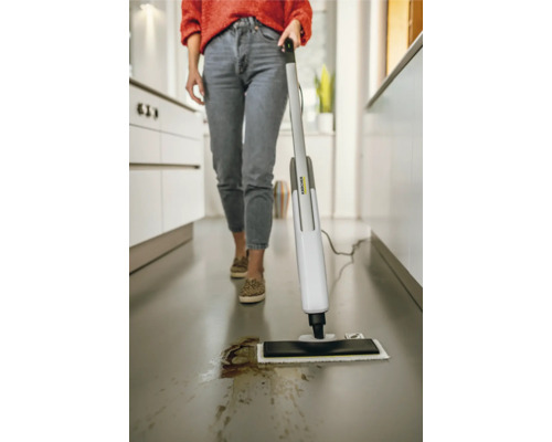 Eine Frau reinigt mit einem Dampfreiniger einen Küchenboden.