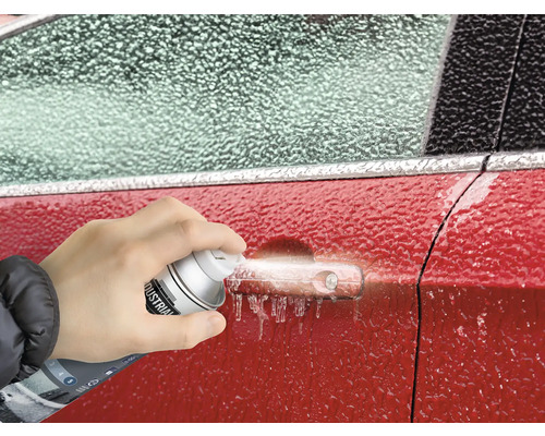 Eine Person sprüht Enteisungsspray auf einen vereisten Autogriff.